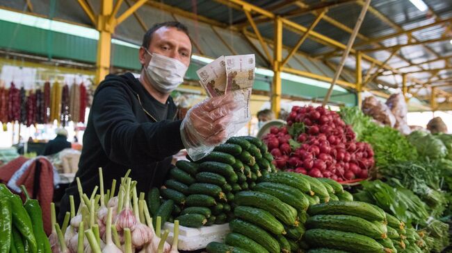 Продавец овощей в медицинской маске на Центральном рынке Адлерского района Сочи