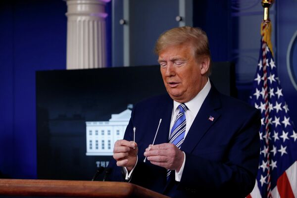 Президент США Дональд Трамп сравнивает обычную ватную палочку с палочкой для забора материала для теста на коронавирус во время ежедневного брифинга 