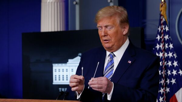 Президент США Дональд Трамп сравнивает обычную ватную палочку с палочкой для забора материала для теста на коронавирус во время ежедневного брифинга 
