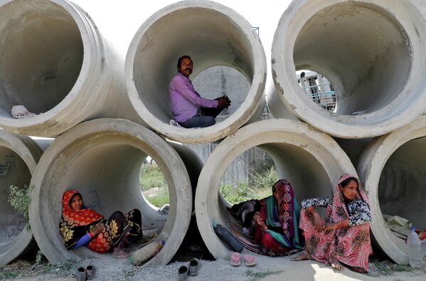 Рабочие-мигранты отдыхают в цементных трубах в Лакхнау, Индия. 22 апреля 2020 года