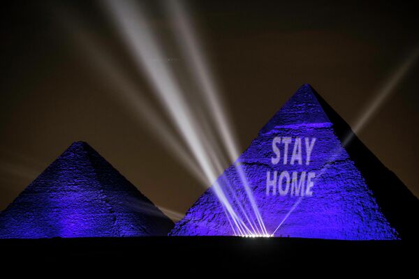 Великие пирамиды освещаются синим светом с надписью оставайся дома на плато Гиза за пределами египетской столицы Каира