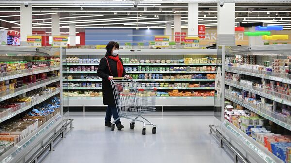 Женщина в защитной маске покупает продукты в гипермаркете