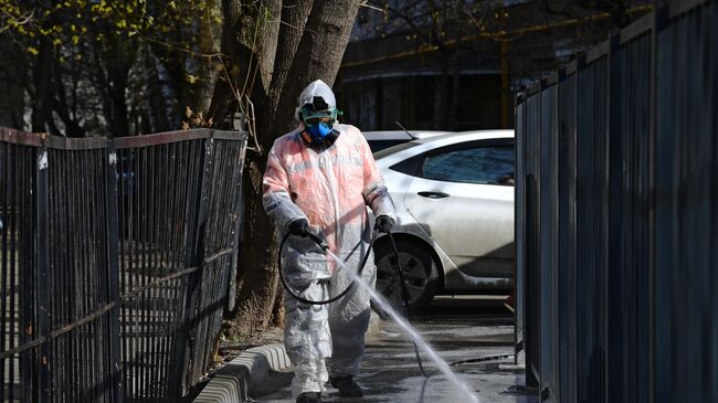 Сотрудник коммунальной службы проводит дезинфекцию внутридворовой территории