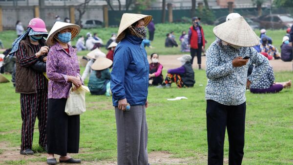 Женщины в защитных масках в очереди за бесплатным рисом в Ханое, Вьетнам