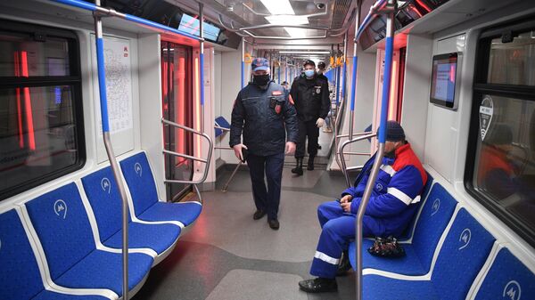 Сотрудники полиции в защитных масках в вагоне московского метро во время рейда по контролю за соблюдением социальной дистанции в 1,5 м
