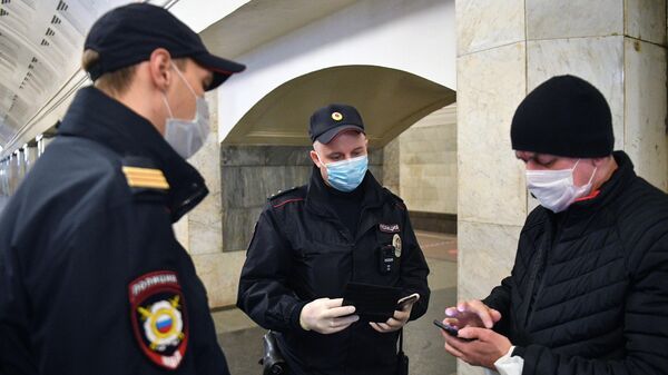 Сотрудники полиции в защитных масках на станции метро  Москвы Охотный ряд проверяют цифровой пропуск у пассажира 