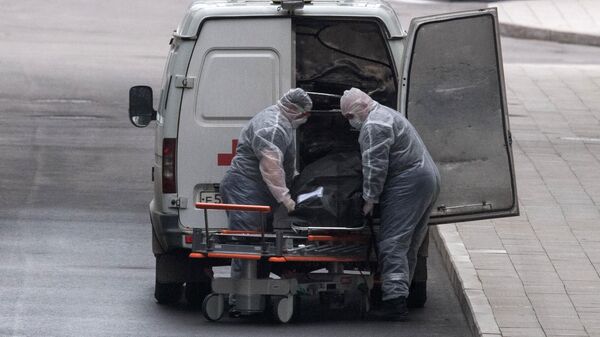 Медицинские работники перевозят тело умершего на территории карантинного центра в Коммунарке