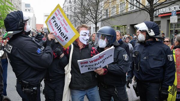 Полиция задерживает демонстранта во время акции протеста против карантинных мер в связи с коронавирусом в Берлине 
