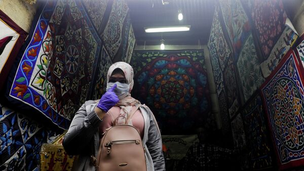 Женщина в защитной медицинской маске в лавке традиционных исламских товаров на рынке в старом Каире, Египет