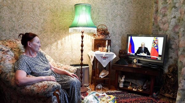 Жительница Москвы смотрит трансляцию совещания президента РФ Владимира Путина с главами регионов по борьбе с распространением коронавируса