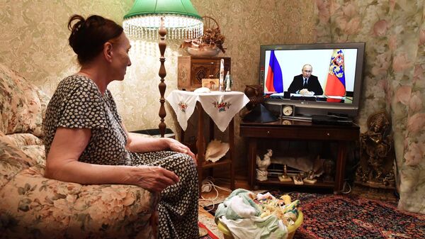 Жительница Москвы смотрит трансляцию совещания президента РФ Владимира Путина с главами регионов по борьбе с распространением коронавируса в России