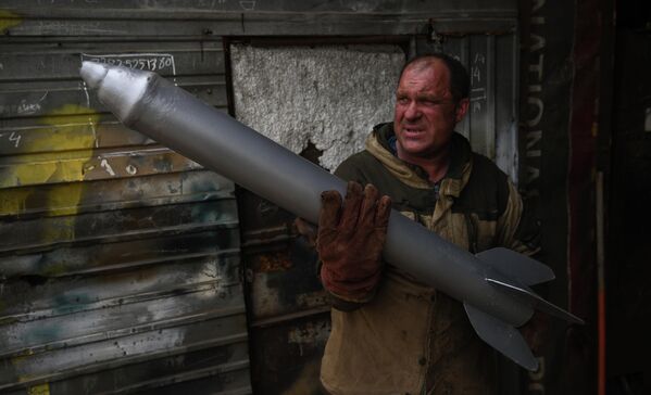 Мастер Максим Свекла держит в руках муляж снаряда для изготовления копии боевой машины Катюша в гараже своего дома в селе Большой Оеш Новосибирской области