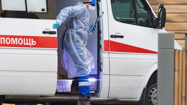 Медик выходит из машины скорой медицинской помощи, доставившей пациента в карантинный центр в Коммунарке