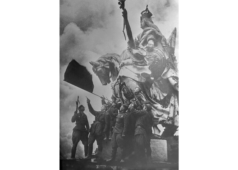 Знамя Победы на здании Рейхстага в Берлине. Солдаты батальона под командованием капитана Степана Неустроева салютуют на крыше Рейхстага