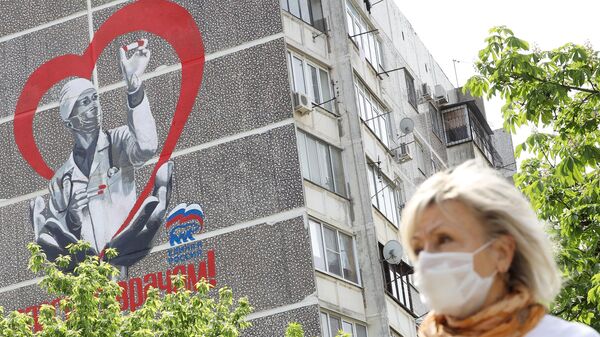 Женщина в медицинской маске около дома с авторским граффити художника Евгения Аморфиса с надписью Спасибо врачам улице 1 мая в Краснодаре