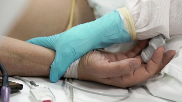 Медицинский работник у постели пациента в стационаре для больных с коронавирусной инфекцией