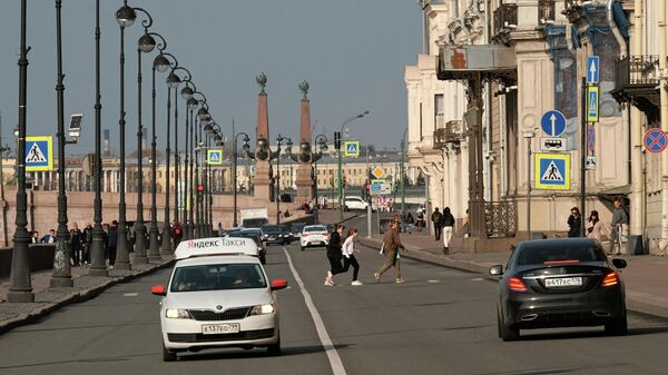 Люди переходят дорогу на Дворцовой набережной в Санкт-Петербурге