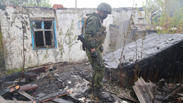 Военнослужащий НМ ДНР осматривает сгоревший после обстрела дом в поселке Шахты 6-7 в Горловке