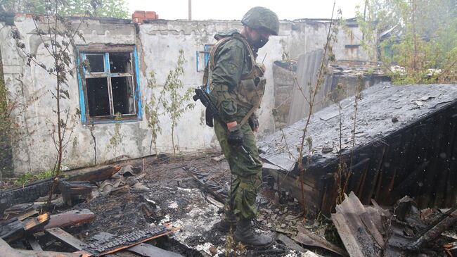 Военнослужащий НМ ДНР осматривает сгоревший дом в поселке Шахты 6-7 в Горловке