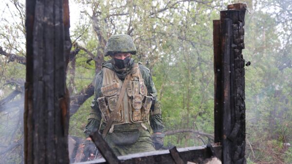 Военнослужащий НМ ДНР осматривает сгоревший дом в поселке Шахты 6-7 в Горловке