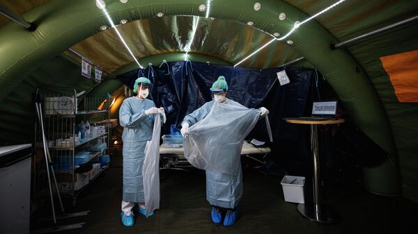 Медицинские работники надевают средства индивидуальной защиты в палатке для тестирования на коронавирус COVID-19 в Стокгольме, Швеция
