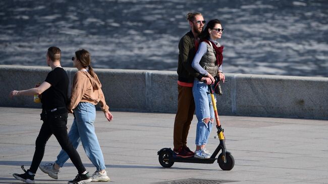 Пара едет на самокате по Москворецкой набережной в Москве