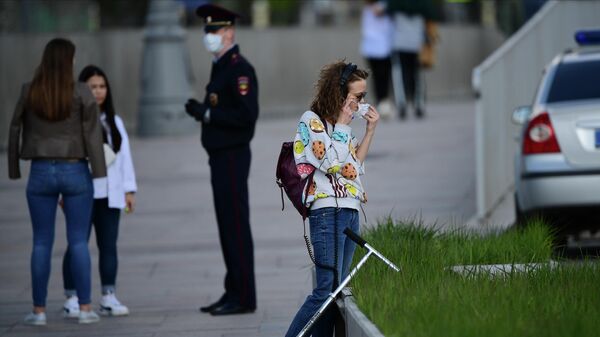 Девушка поправляет защитную маску на улице в Москве