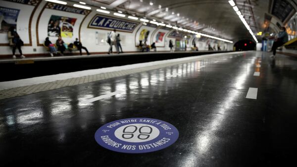 Стикер с призывом соблюдать дистанцию на одной из станций метро в Париже 