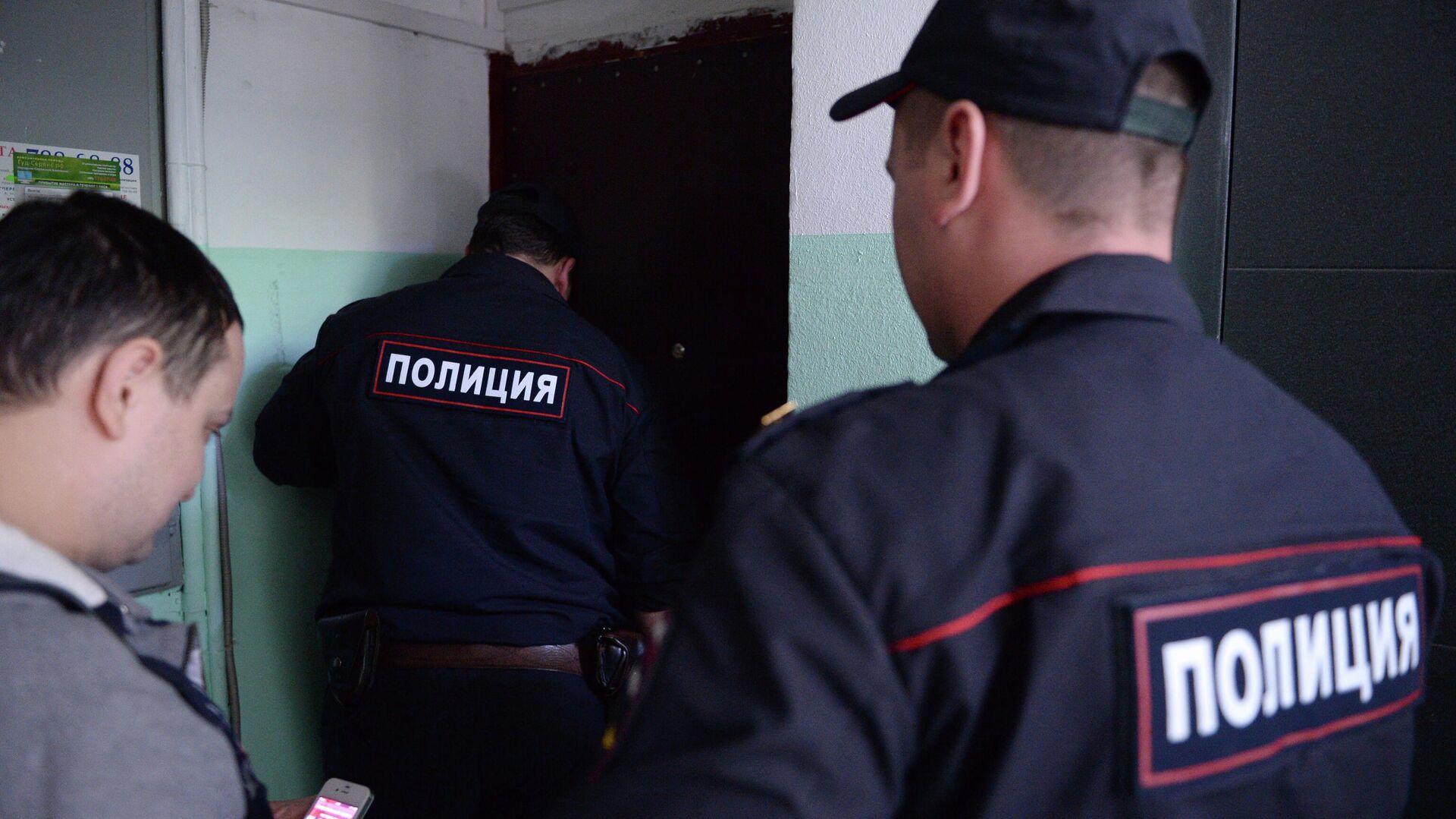 Сотрудники полиции стоят у двери квартиры в жилом доме - РИА Новости, 1920, 03.12.2022