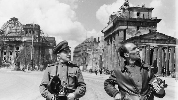 Фронтовые кинооператоры-напарники Илья Аронс (слева) и Леон Мазрухо у Бранденбургских ворот и Рейхстага. Берлин, май 1945 год