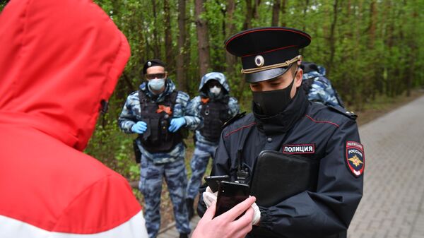 Сотрудник полиции совместно с сотрудниками Росгвардии проверяют документы у прохожих в Бирюлевском лесопарке Москвы