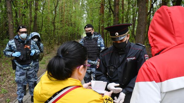 Сотрудник полиции совместно с сотрудниками Росгвардии проверяют документы у прохожих в Бирюлевском лесопарке Москвы