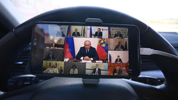 Мужчина смотрит трансляцию обращения президента России Владимира Путина в связи с ситуацией, связанной с распространением коронавируса в своем автомобиле в Москве