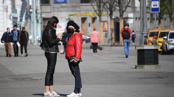 Девушки в медицинских масках на одной из улиц в Москве