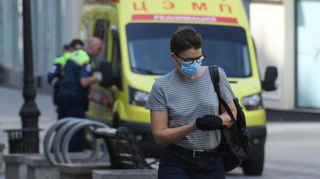 Девушка в медицинской маске и перчатках на одной из улиц в Москве