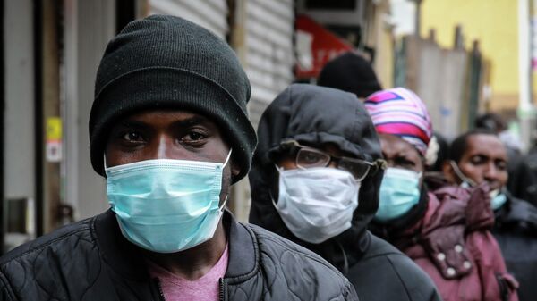 Люди в очереди за масками и едой в районе Гарлема в Нью-Йорке, США