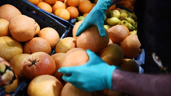 Покупатель выбирает фрукты в продуктовом магазине в Москве