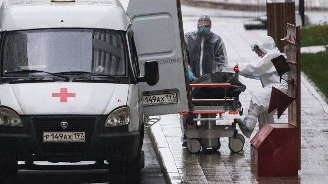 Медики перевозят тело умершего на территории карантинного центра в Коммунарке