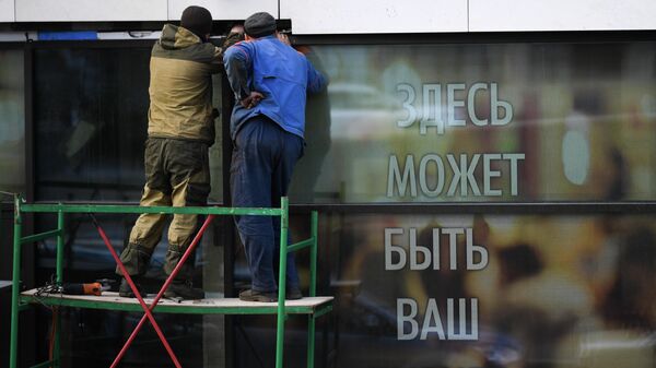 Мужчины ремонтируют витрину магазина в Москве во время режима самоизоляции жителей