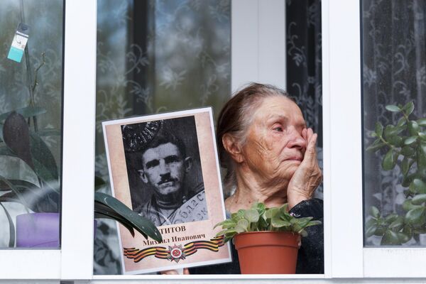 Жительница Иркутска на балконе с портретом своего родственника - ветерана Великой Отечественной войны в рамках акции Окна Победы