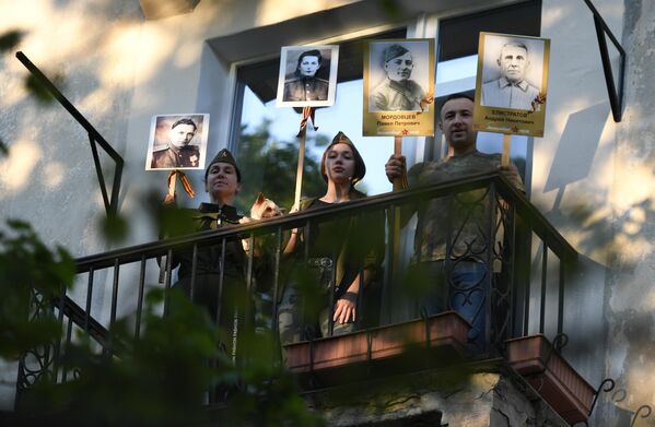 Жители дома с портретами родственников-фронтовиков поют песни на балконе в рамках всероссийской акции #ПоемДеньПобеды в Севастополе