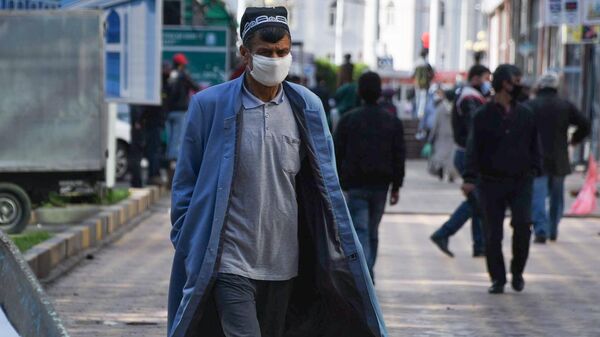 Мужчина в защитной маске на одной из улиц в Душанбе