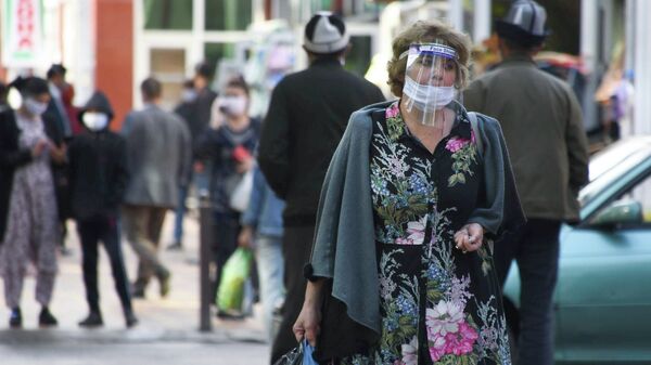 Женщина в защитной маске на одной из улиц в Душанбе