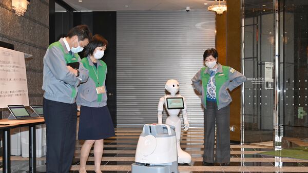 Робот, обслуживающий зараженных коронавирусом на обсервации в токийских гостиницах. Справа губернатор Токио Коикэ Юрико