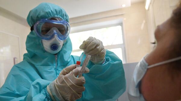 Медицинский работник в защитном костюме проводит забор биоматериала для анализа на коронавирус в городской поликлинике Москвы