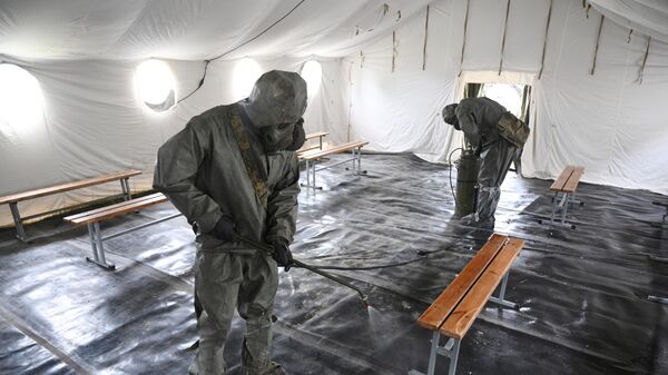Военнослужащие подразделения войск радиационной, химической и биологической защиты дезинфицируют помещение