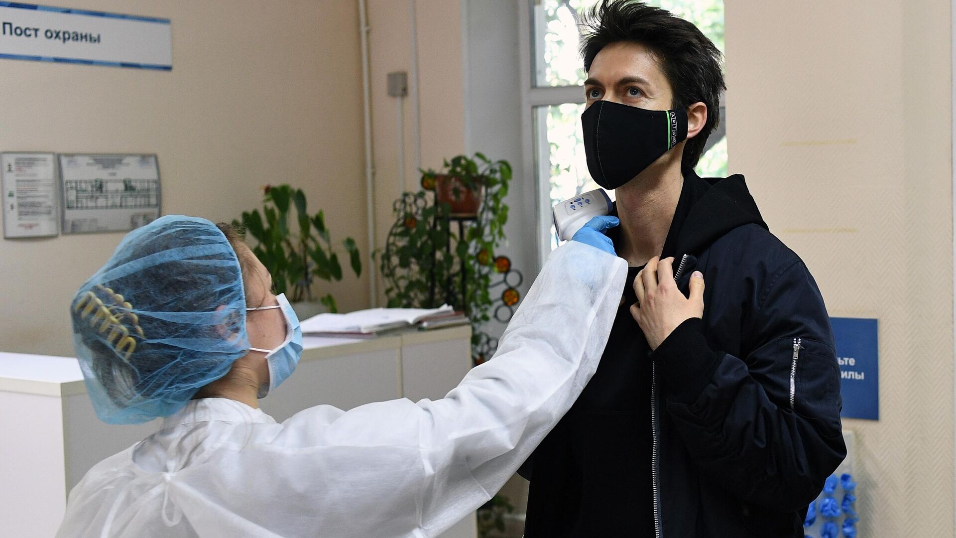 Медицинский работник измеряет температуру у мужчины перед сдачей анализа на антитела к коронавирусу COVID-19 в одной городских поликлиник в Москве - РИА Новости, 1920, 14.02.2021