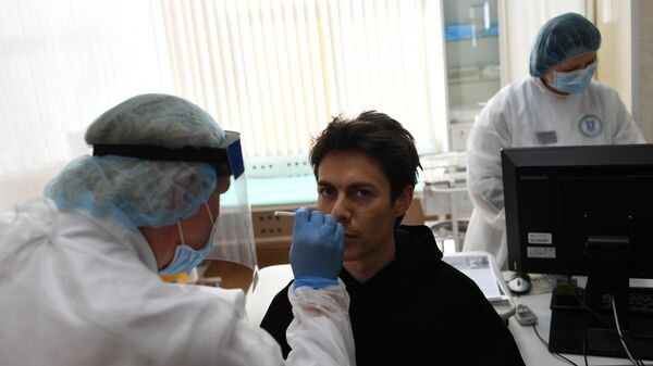 Мужчина во время взятия мазка для анализа на коронавирус COVID-19 в одной городских поликлиник в Москве