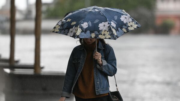 Девушка идет под зонтом во время дождя