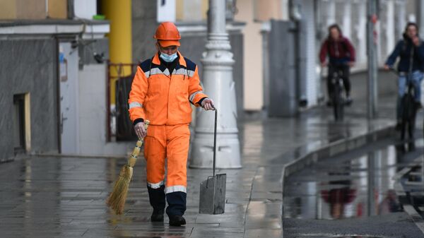 Сотрудник коммунальной службы убирает улицу в Москве